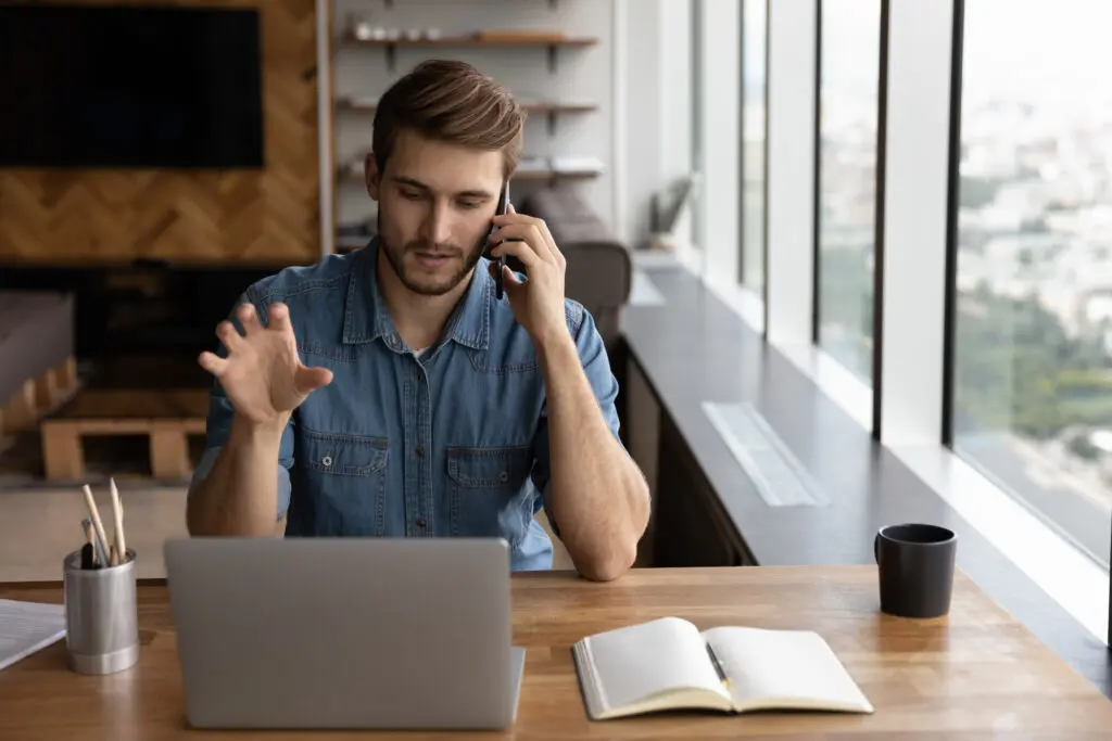 A man sitting at a table talking on the phone.