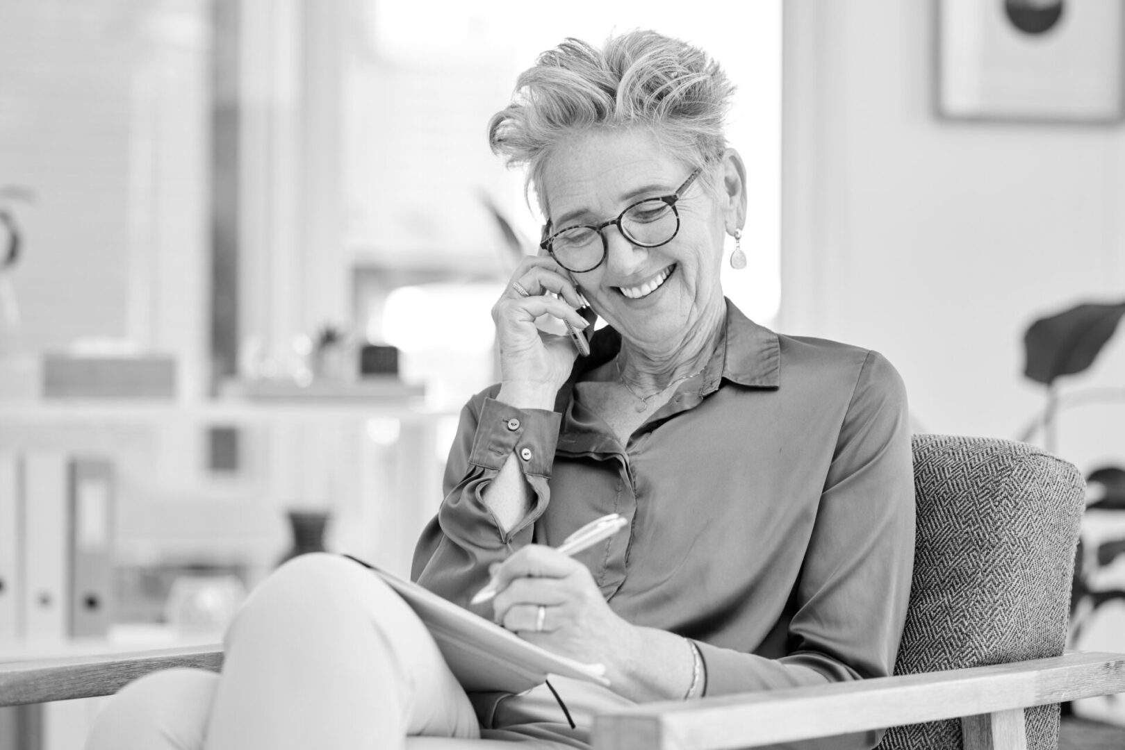 A woman sitting on the couch talking on her phone.