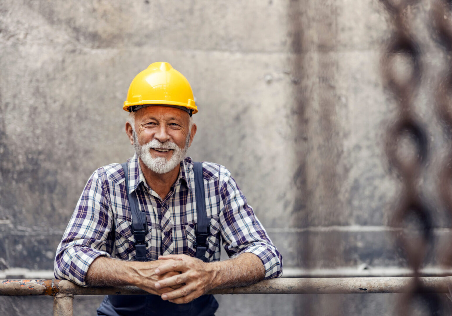 A man in plaid shirt and yellow hard hat.