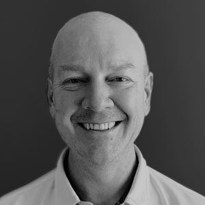 A black and white photo of a man smiling.